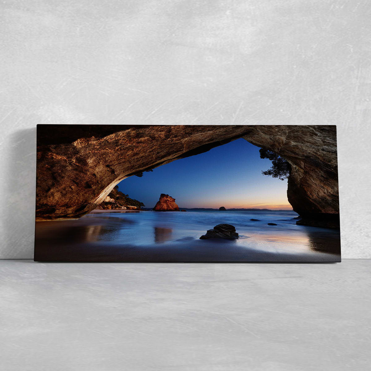 Beach wall art for living room featuring the iconic Cathedral Cove rock formation with ocean reflections at sunrise.