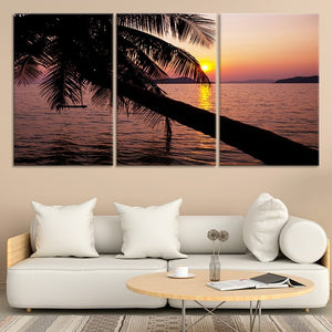 Beach wall art for living room featuring a serene sunset with swaying palm fronds over the ocean.