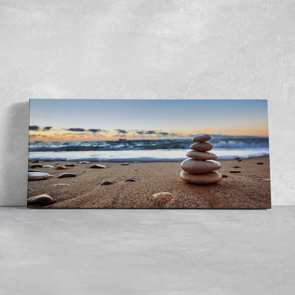 Extra large ocean wall art showcasing a peaceful stack of balancing pebbles on the beach with gentle waves.