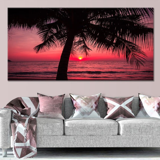 Large beach wall art featuring a striking red sunset over the ocean, framed by a silhouetted palm tree.