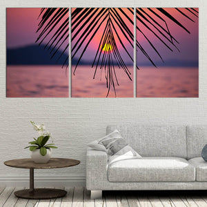 Large canvas beach wall art depicting a glowing sunset over calm ocean waters with palm leaf shadows.